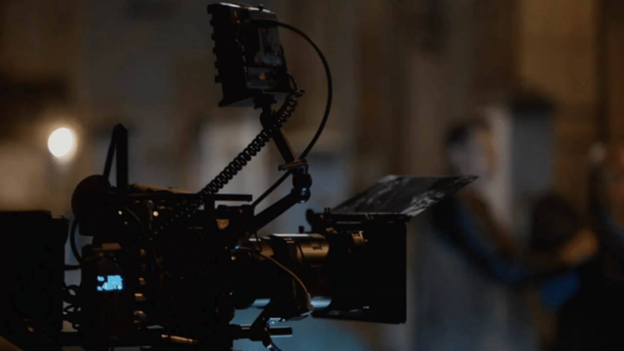 Cinematic camera rig with an external monitor on a flexible arm in a dim studio setting.